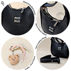 Black handbag with metal embellishments, silver zipper, teddy bear keychain, and faux leather strap on a white background.