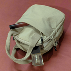 Beige bag with a pen and small device on a red background