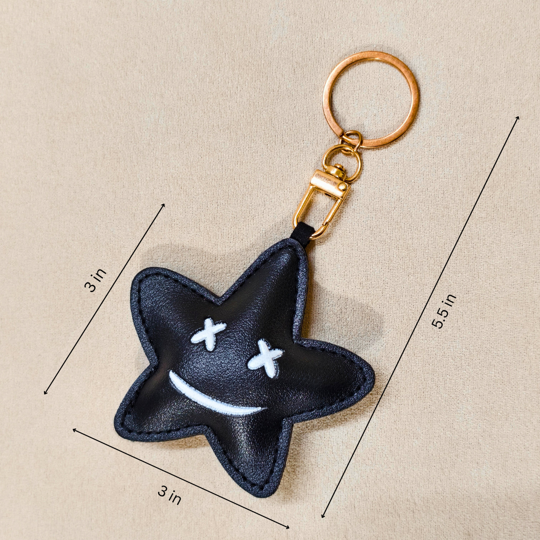 Black star-shaped keychain with white accents on a beige background with measurements.