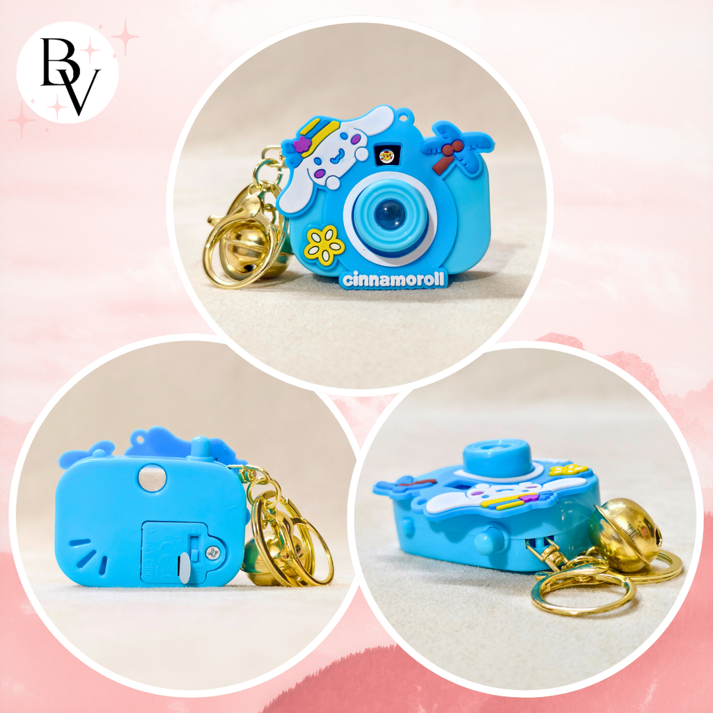 Blue camera-shaped keychain with a gold chain on a pink background