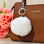 Keychain Displayed On Bag In Front Of Beige Background.