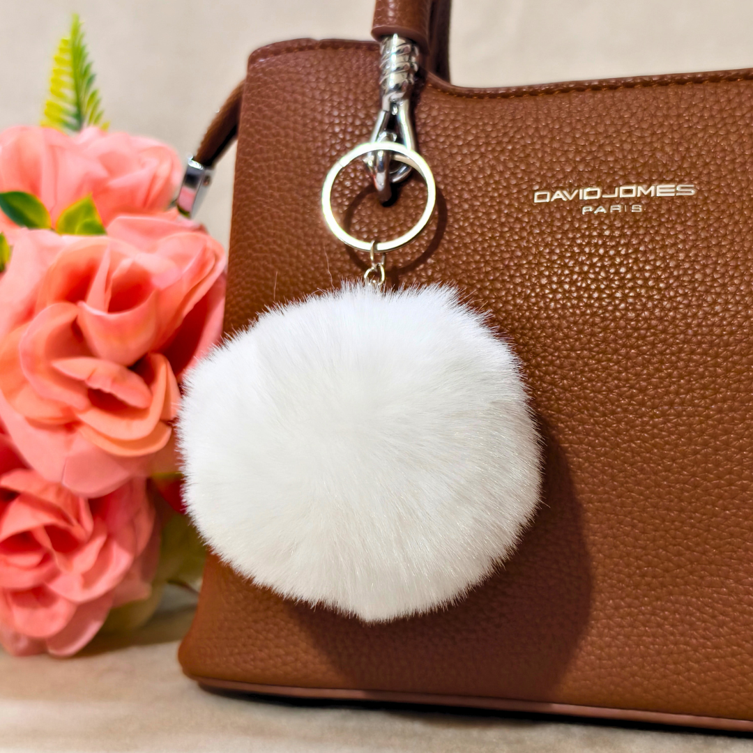 Keychain Displayed On Bag In Front Of Beige Background.