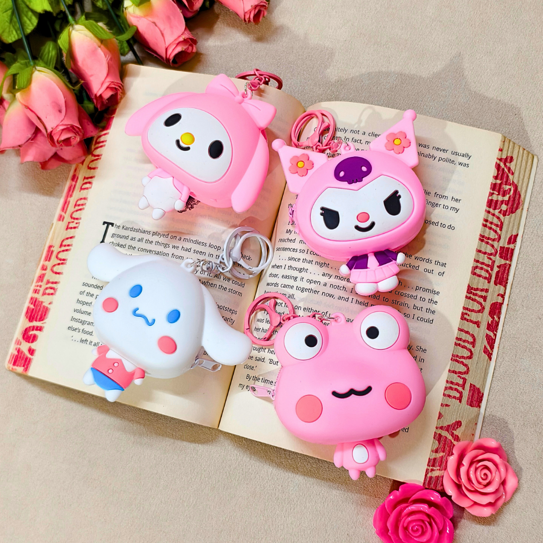 Four pink cartoon character keychains on an open book with pink flowers.