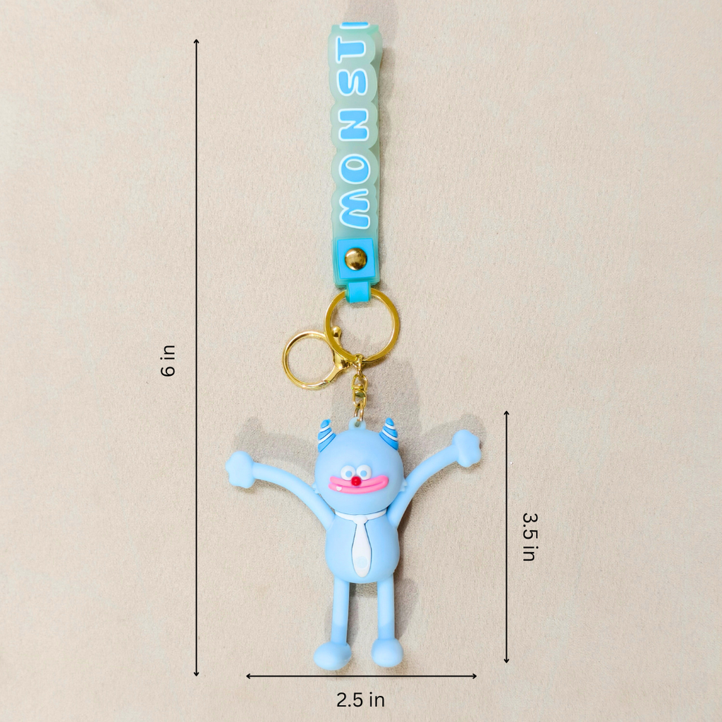 A light blue monster-shaped keychain charm with gold metal rings and a turquoise strap printed with the word 'MONSTERS' in light blue letters. The image includes dimension lines and text indicating the product's measurements: 6 in total height, 3.