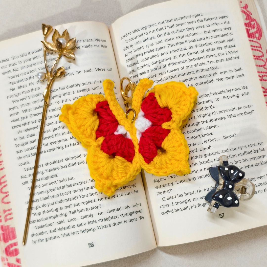 Butterfly-shaped keychain on an open book with a decorative hairpin.