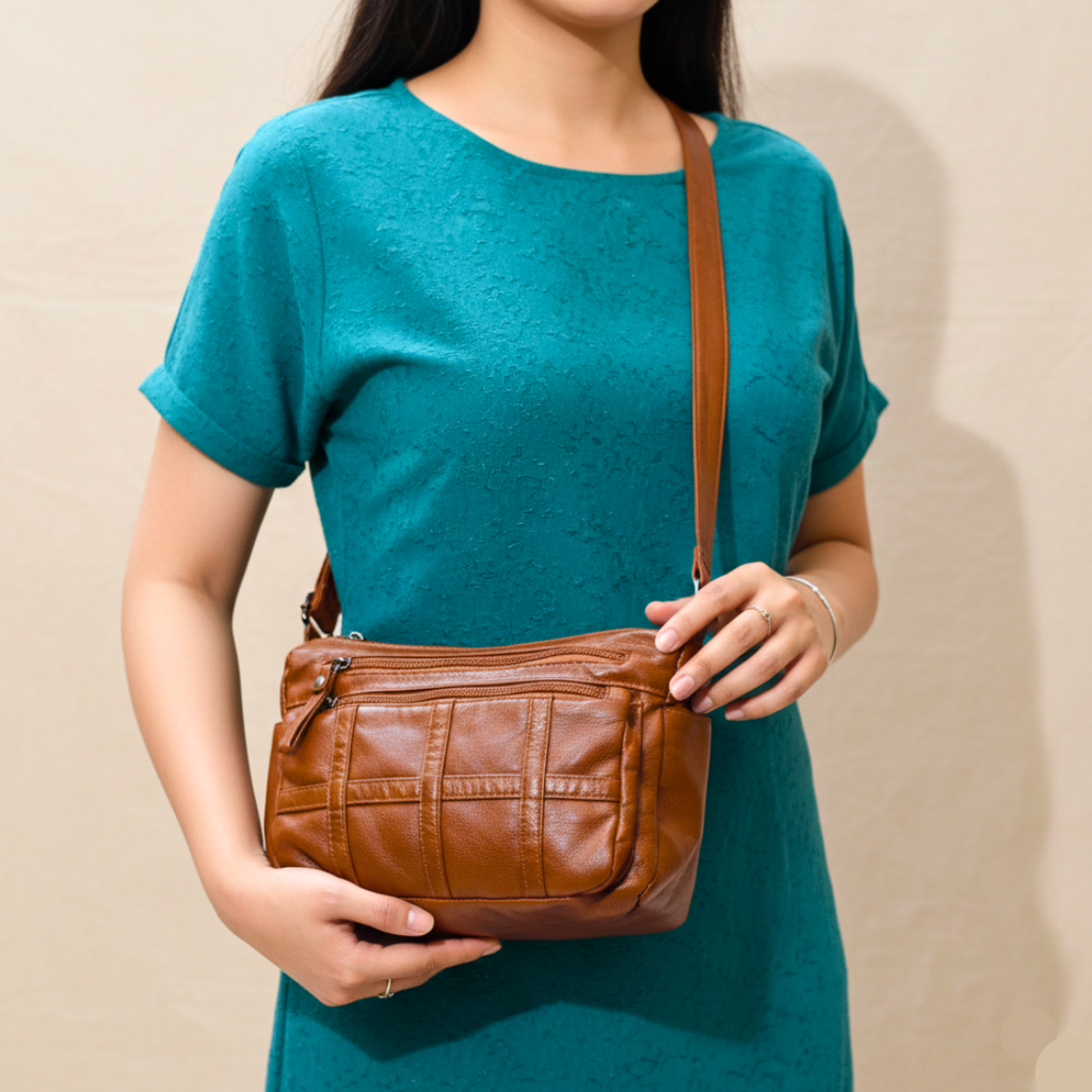 Person holding a brown leather handbag against a beige background