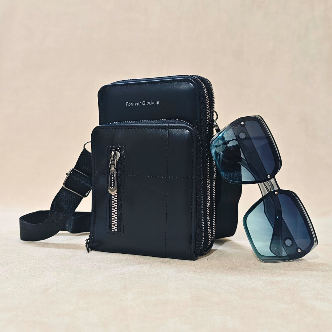 Black leather crossbody bag with sunglasses on a beige background