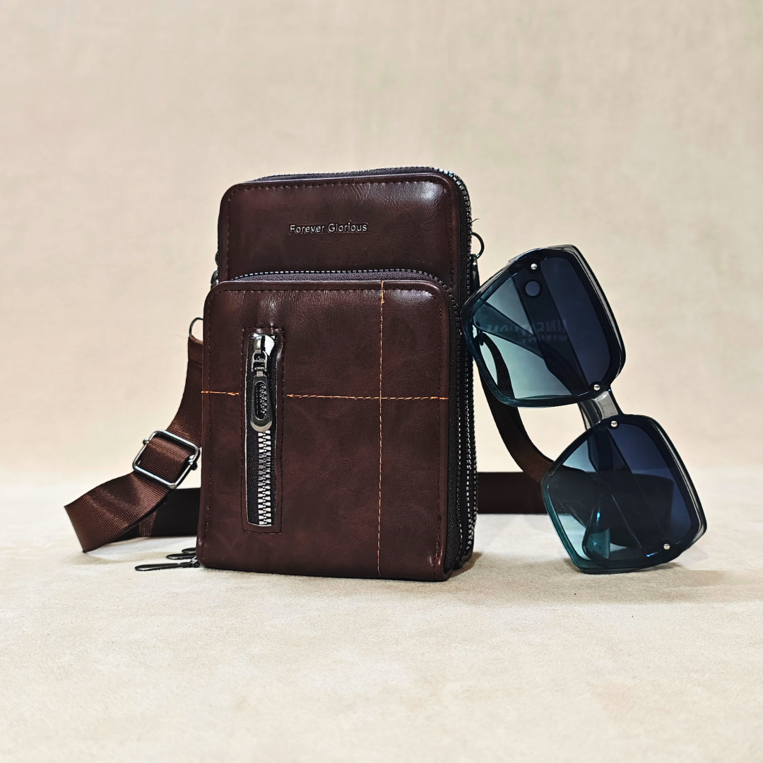 Brown leather crossbody bag with sunglasses on a beige background