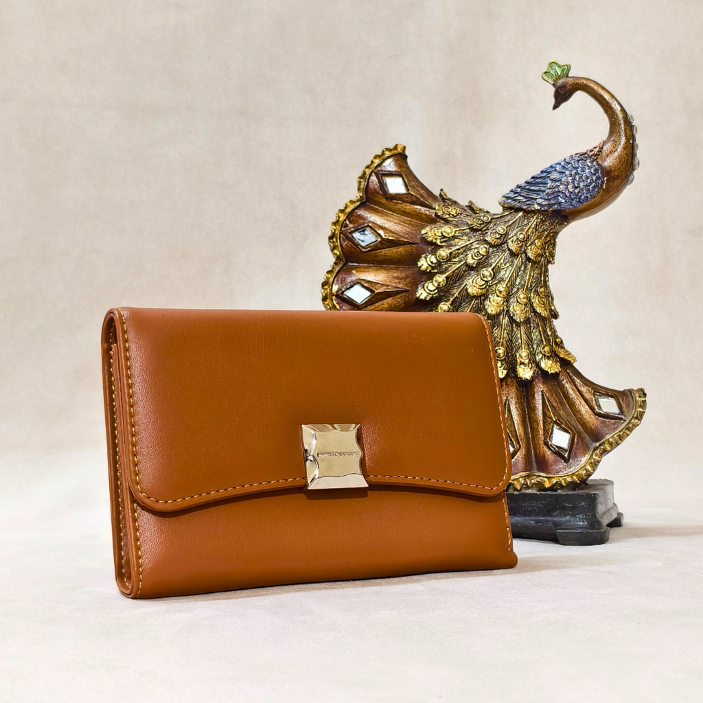 Brown wallet with gold clasp in front of a decorative peacock statue on a beige background