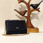 Black handbag with gold chain and 'Pierre' branding on a beige background