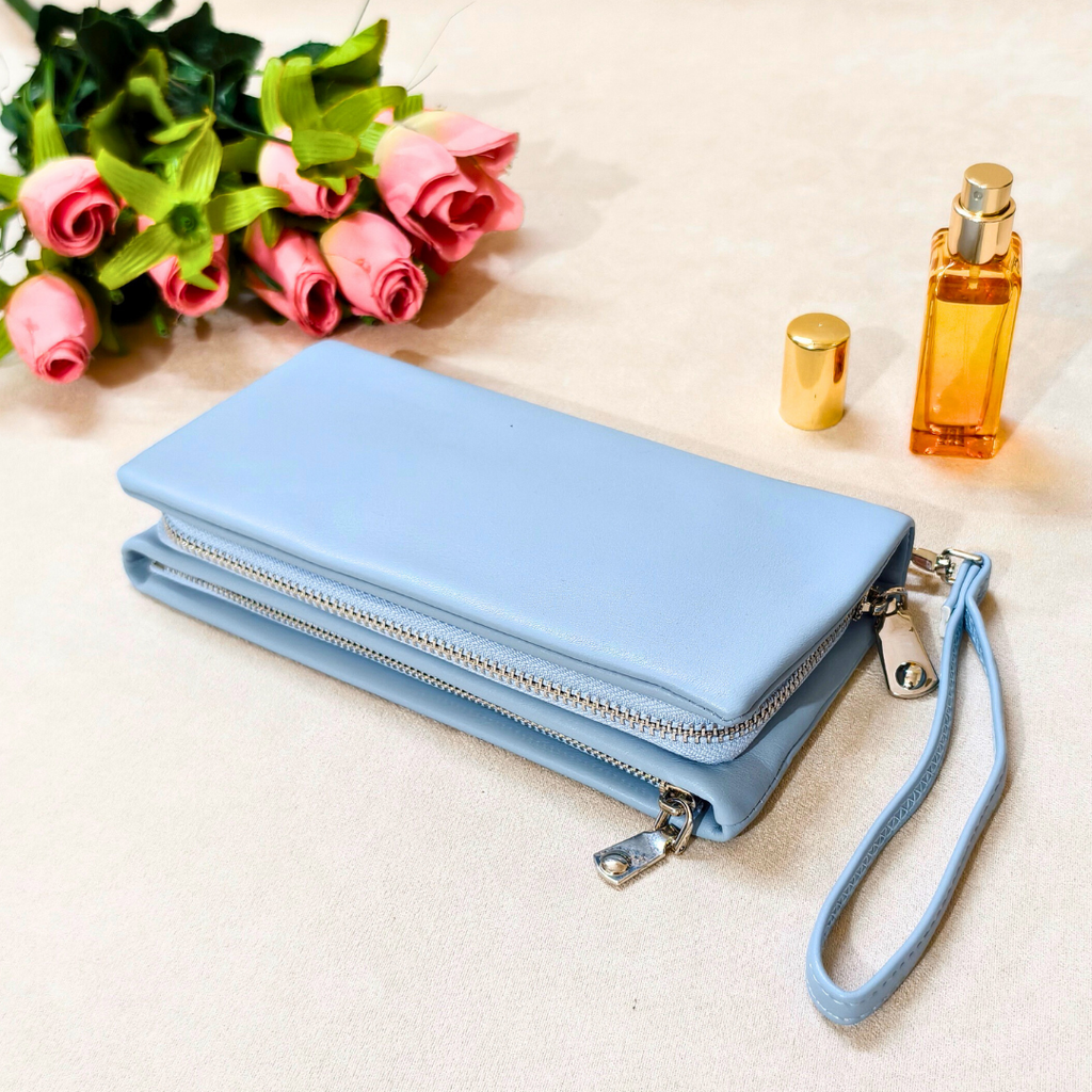 Blue wallet with a strap, flowers, and perfume bottle on a light background