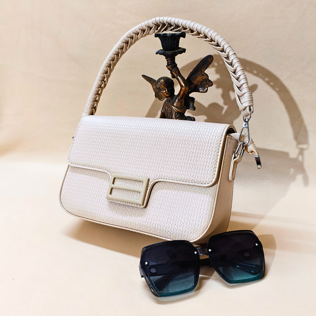 White handbag with braided handle and sunglasses on a beige surface