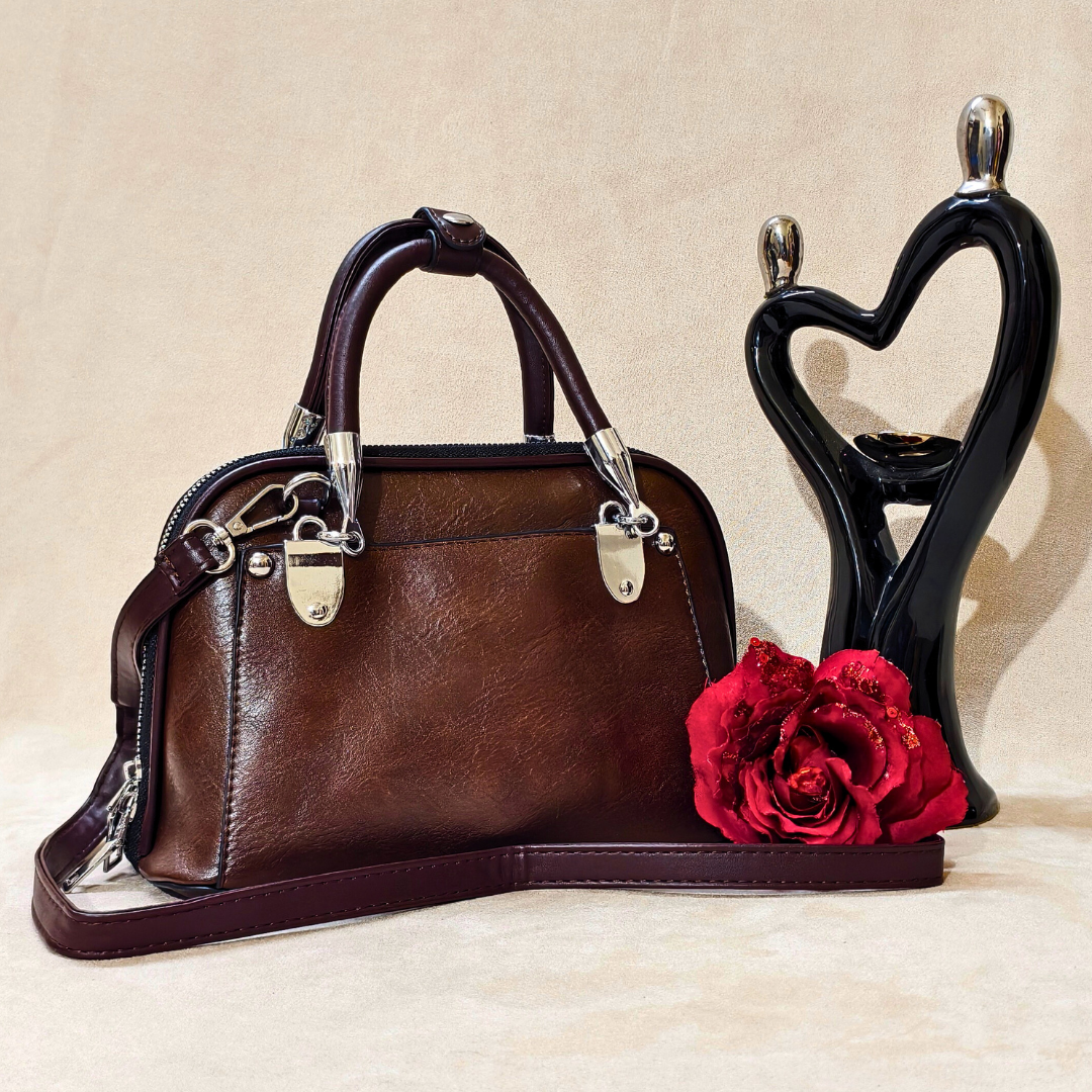 Brown handbag with a red rose on a beige surface