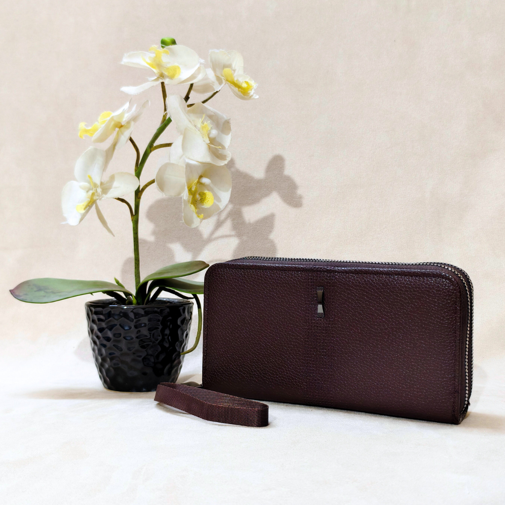 Brown leather wallet and white orchid plant on a light background