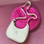 Beige handbag with a pink textured ball on a pink background