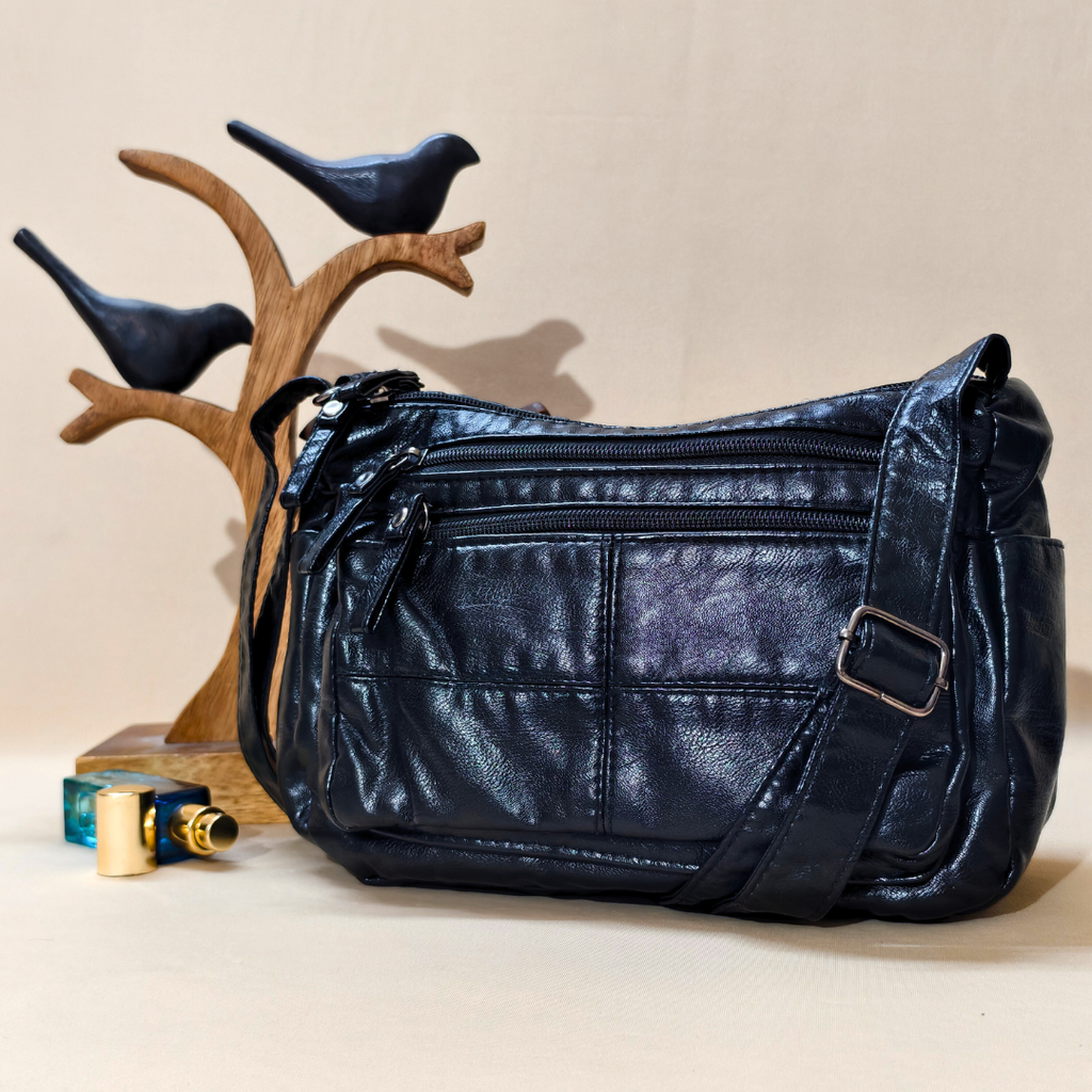 Black leather handbag on a beige surface with decorative birds and a wooden stand in the background.