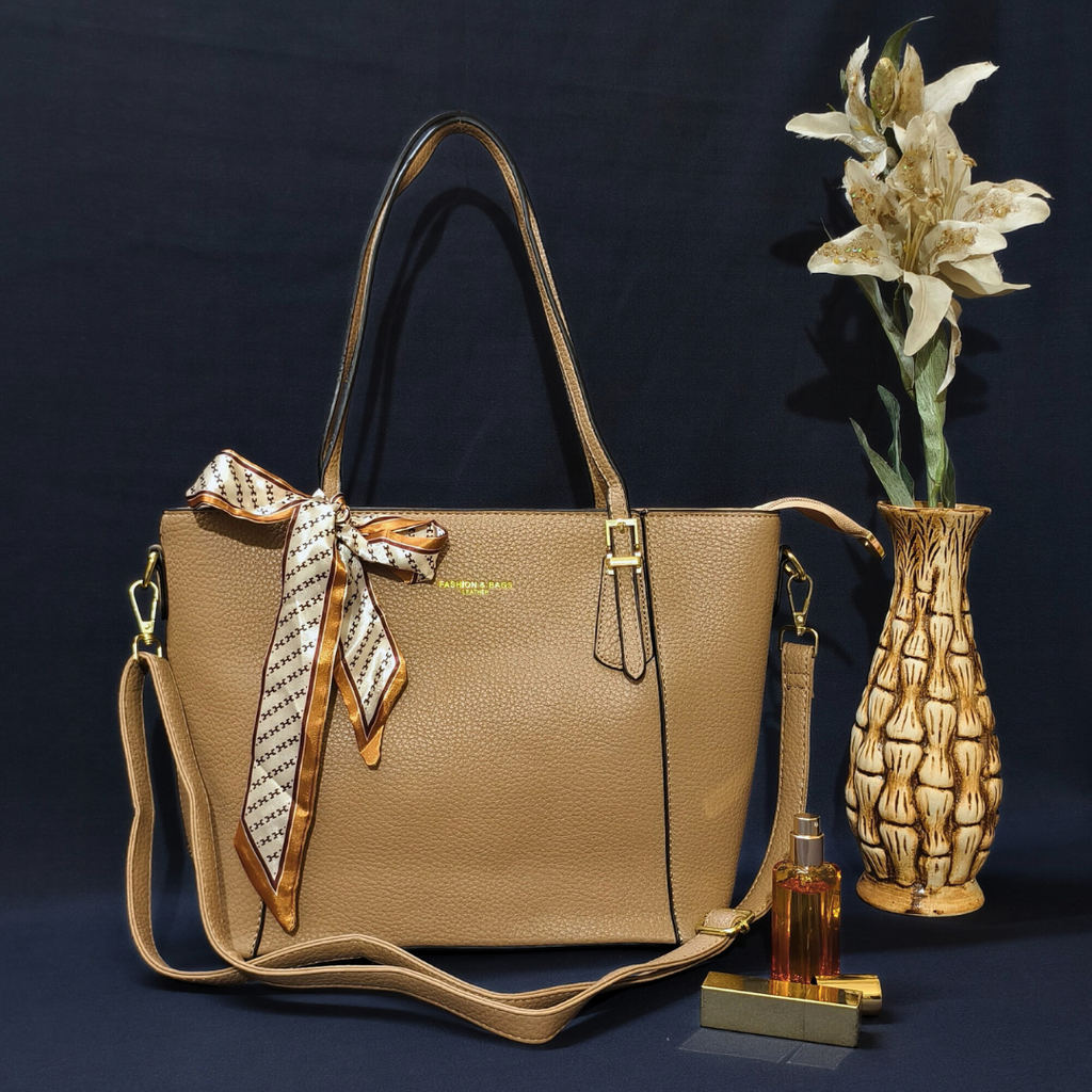 Beige handbag with a decorative bow, accompanied by a vase and bottle on a dark background