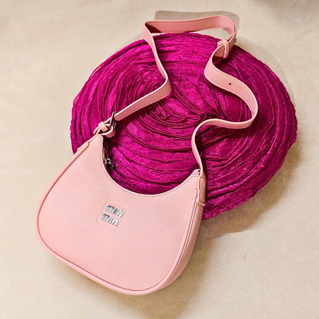 Pink handbag with a textured pink strap on a beige background