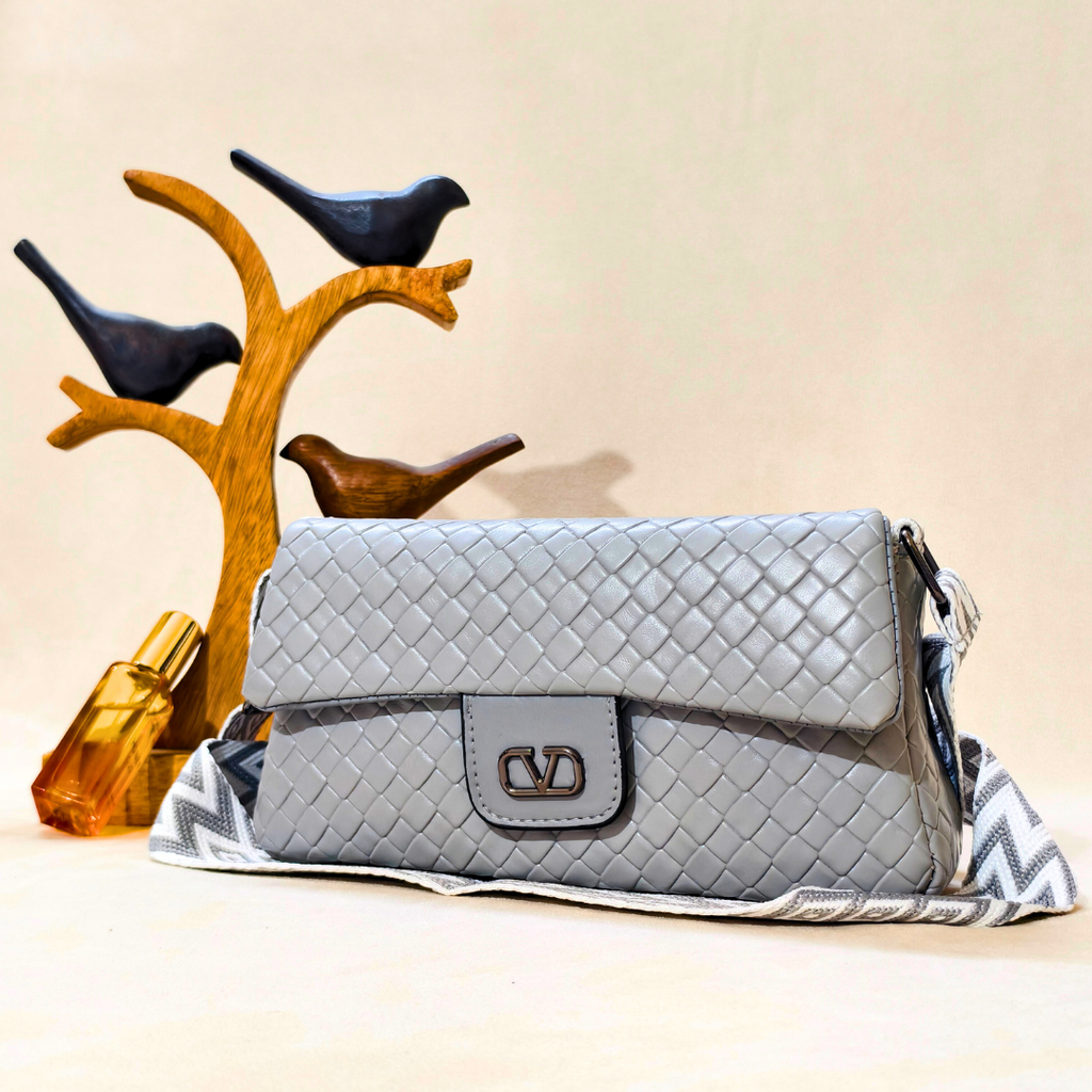 Gray quilted handbag with a decorative strap on a beige background