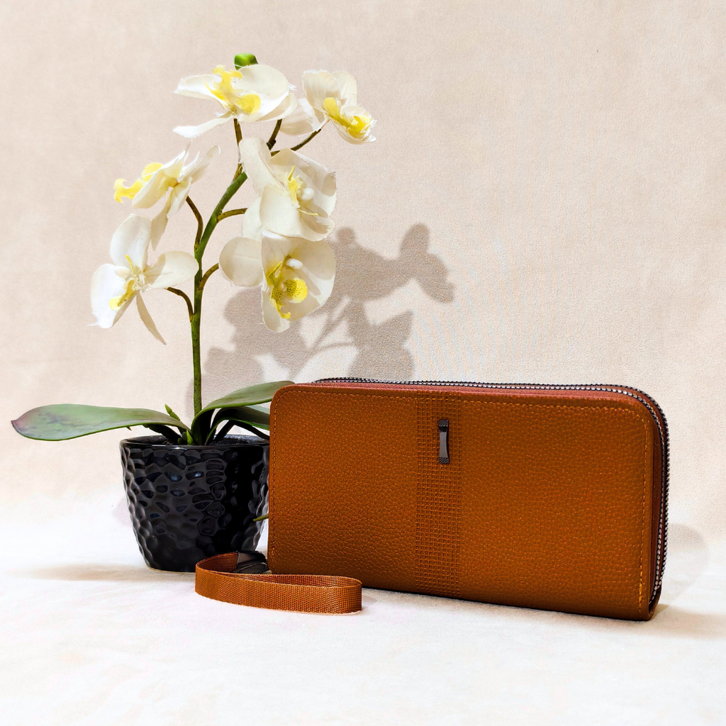 Brown wallet next to a potted orchid on a light background