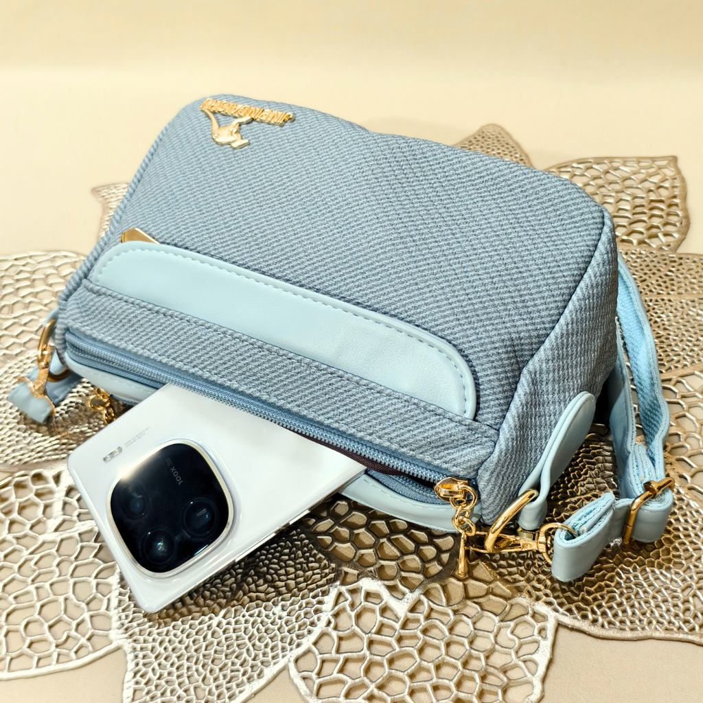 Light blue textured handbag with gold accents on a textured surface
