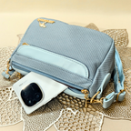 Light blue textured handbag with gold accents on a textured surface