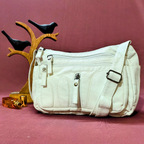 White handbag on a pink background with decorative birds and a small tree branch.