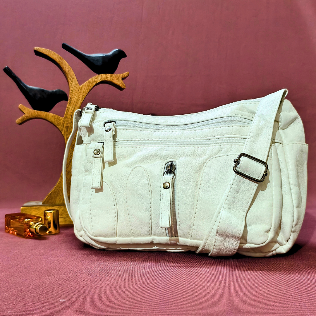White handbag on a pink background with decorative birds and a small tree branch.