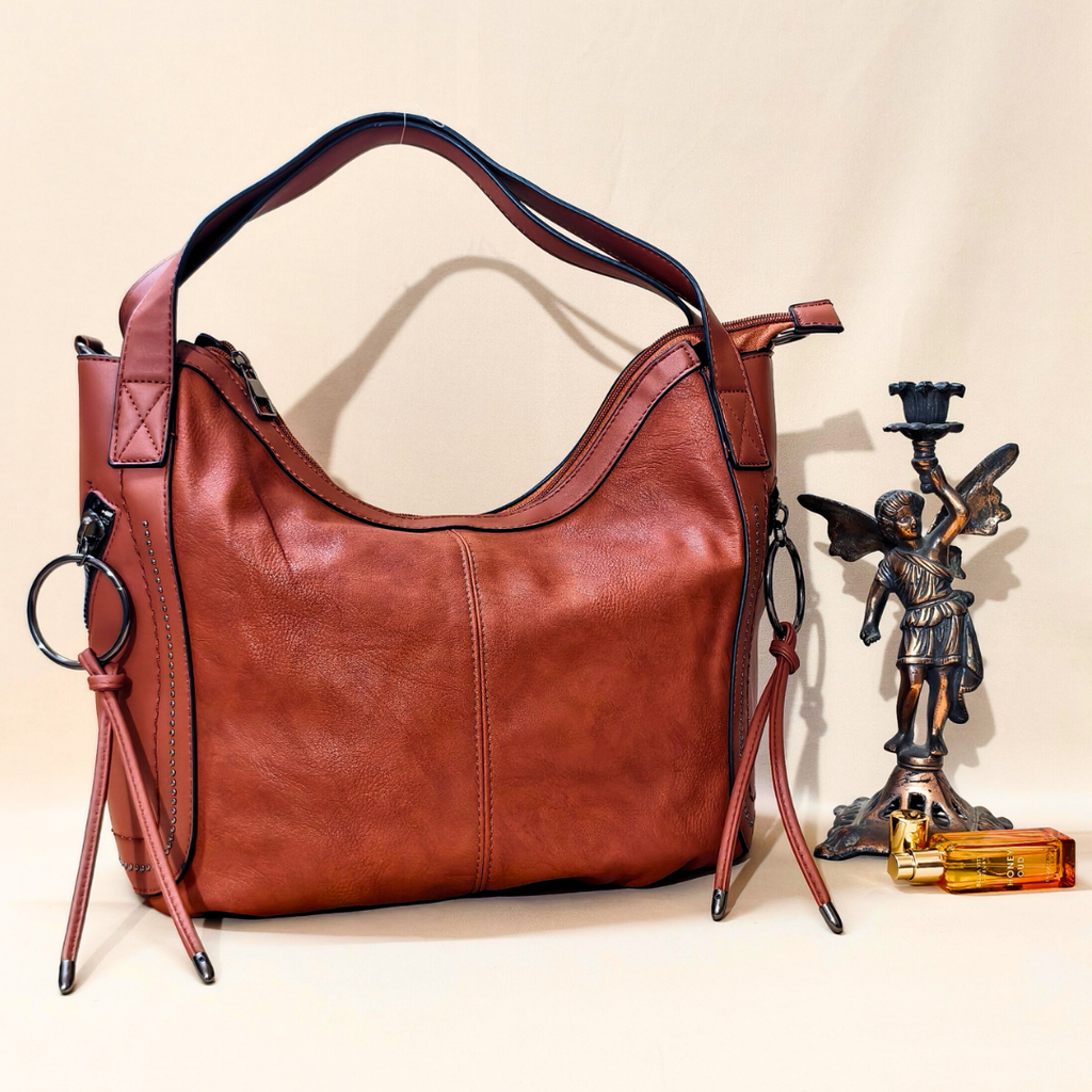 Brown leather handbag with decorative elements on a beige background