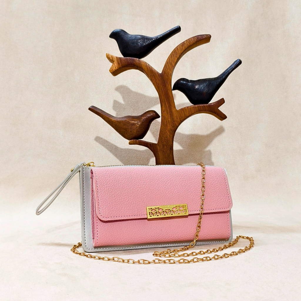 Pink handbag with gold chain and gray base, placed on a wooden bird stand against a beige background.