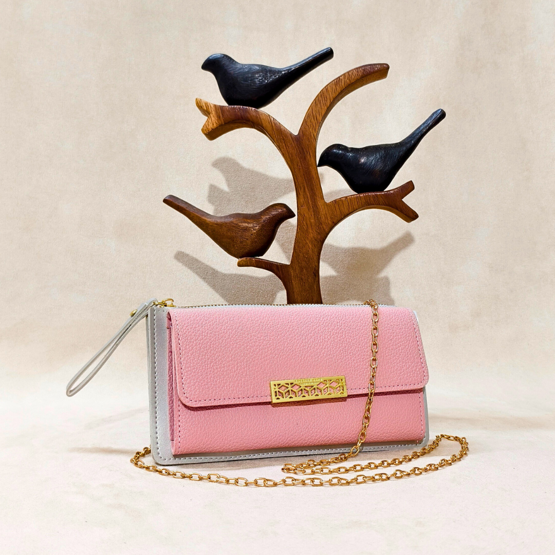 Pink handbag with gold chain and gray base, placed on a wooden bird stand against a beige background.