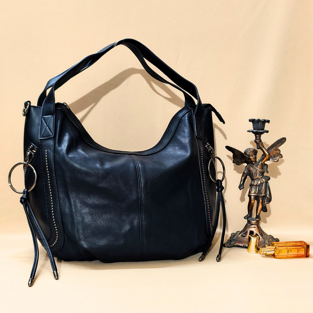 Black leather handbag on a beige background with decorative items.
