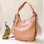 Pink handbag with decorative peacock figure on a beige background