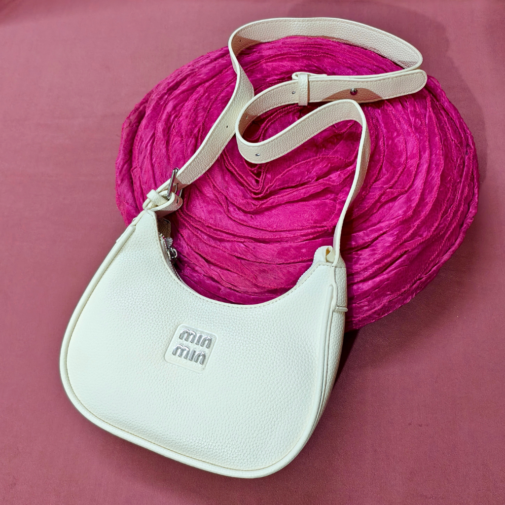 White handbag with beige strap on a pink textured background