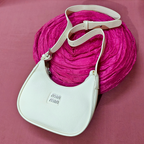 White handbag with beige strap on a pink textured background