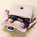 Beige handbag with sunglasses and a blue bottle on a beige background