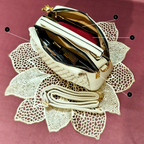 Beige handbag with gold accents on a decorative lace background