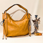 Brown leather handbag on a white surface with decorative items.