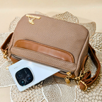 Brown textured handbag with gold accents on a textured surface