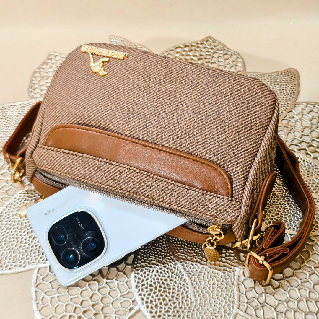 Brown textured handbag with gold accents on a textured surface