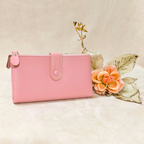 Pink wallet on a beige surface with decorative flowers