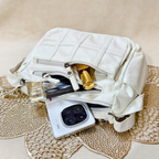 White quilted handbag with a phone and other items on a textured surface
