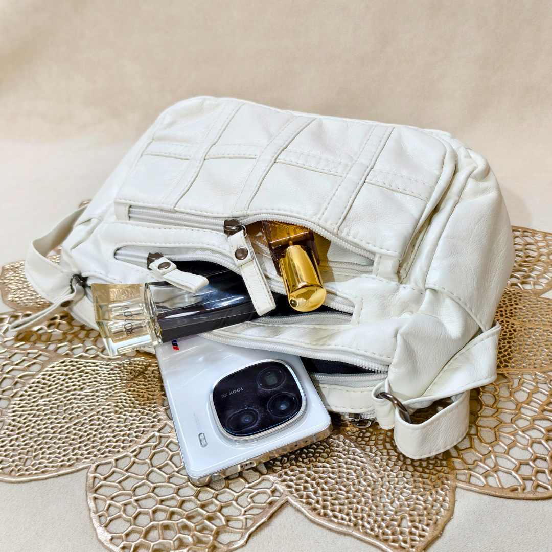 White quilted handbag with a phone and other items on a textured surface