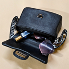 Black handbag with sunglasses and a bottle on a beige background