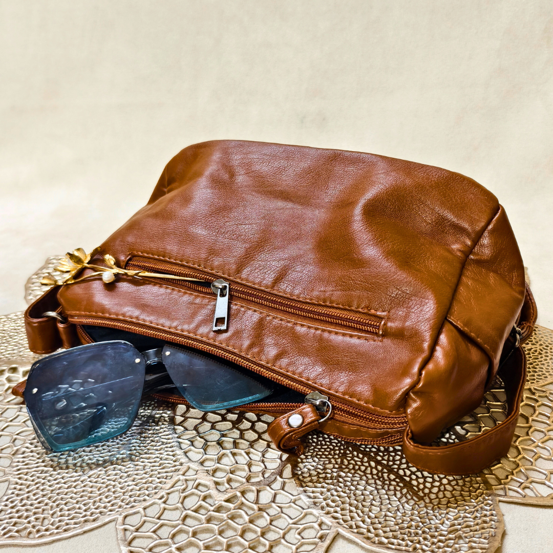 Brown leather bag with sunglasses on a textured surface