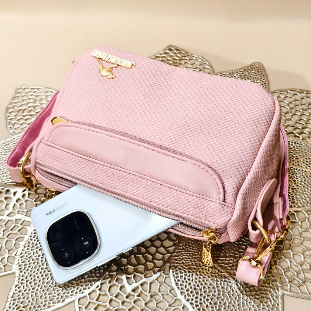 Pink handbag with gold accents on a textured surface