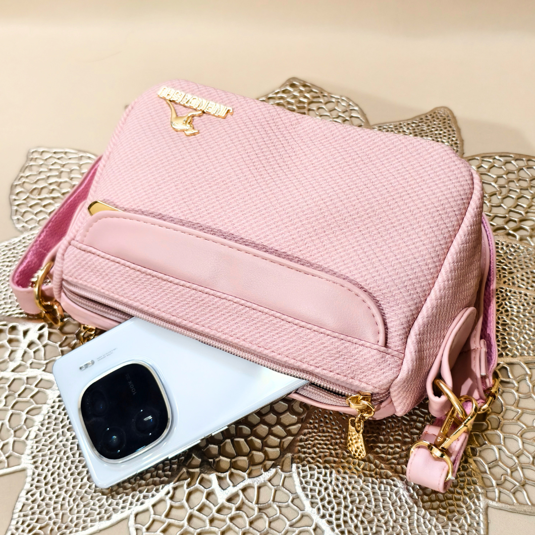Pink handbag with gold accents on a textured surface