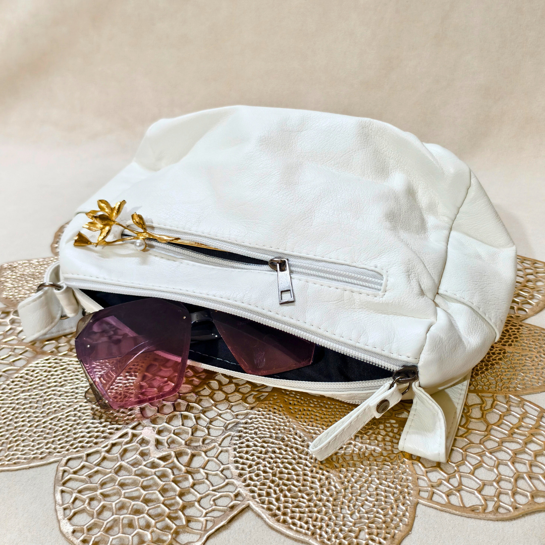White handbag with sunglasses on a textured beige surface