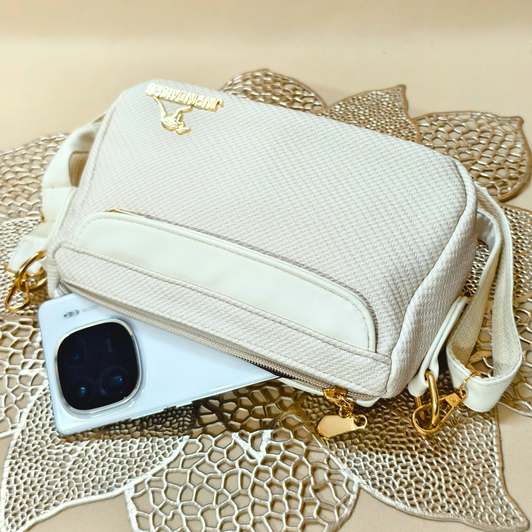 Beige handbag with gold accents on a textured surface