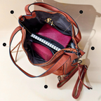 Brown leather handbag with open design showing interior compartments on a beige background